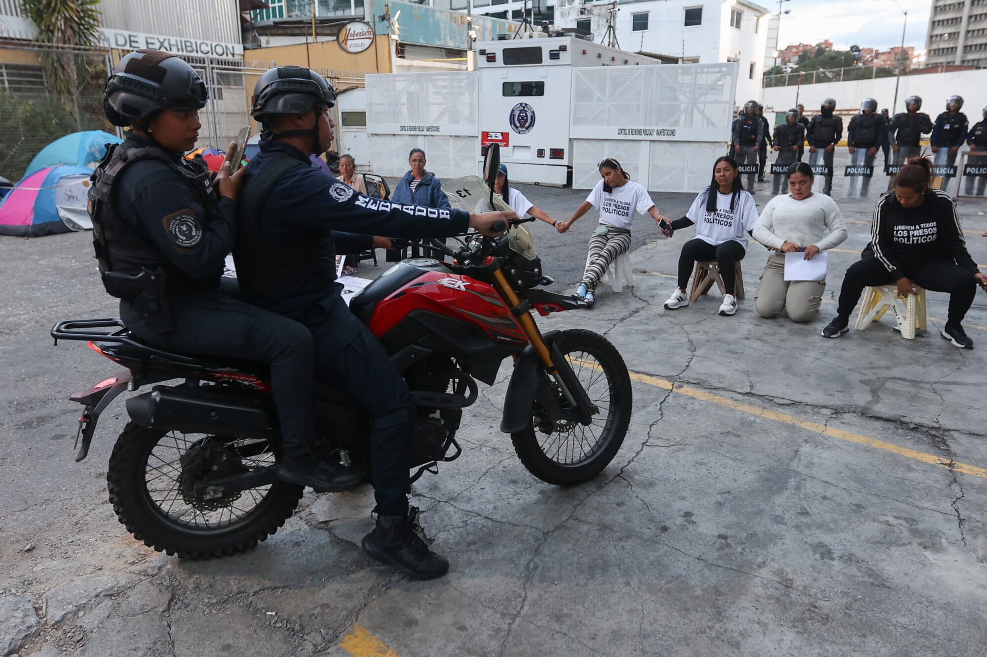<em>Unas mujeres que esperan noticias sobre la liberación de presos frente a la Zona 7 de la Policía Nacional Bolivariana (PNB) en el municipio Sucre del Distrito Metropolitano de Caracas (DMC) el 26 de enero de 2026. (Pedro MATTEY / AFP vía Getty Images)</em>