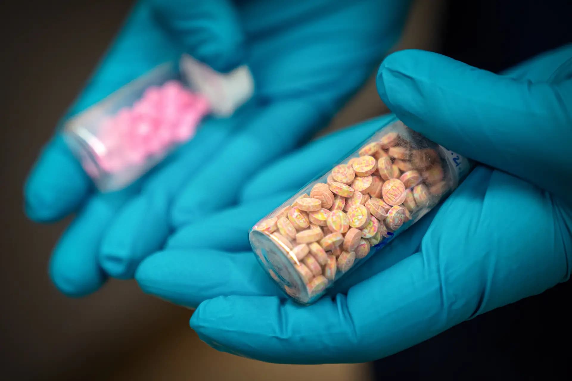 <em>Jonathan Dumke, químico forense senior de la Administración para el Control de Drogas, sostiene viales de pastillas de fentanilo en un laboratorio de investigación de la DEA en el norte de Virginia el 29 de abril de 2025. (Angela Weiss/AFP vía Getty Images, Mark Schiefelbein/AP Photo, archivo)</em>