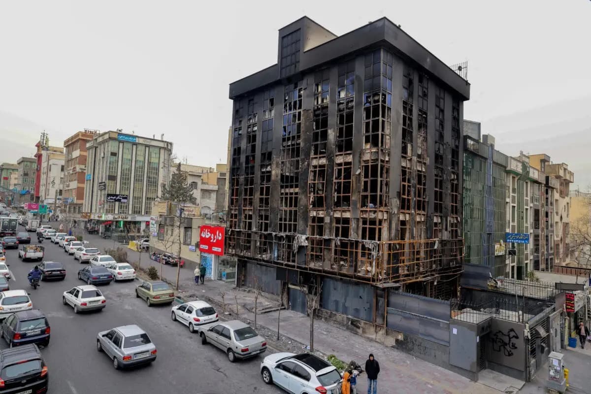 La gente pasa junto a un edificio destruido durante las protestas públicas en Teherán, Irán, el 19 de enero de 2026. (Atta Kenare/AFP vía Getty Images).