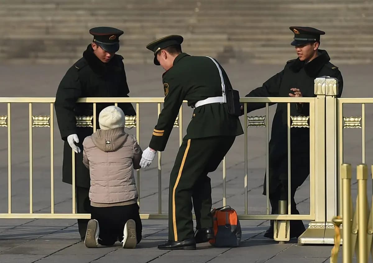 Agentes de la policía paramilitar detienen a una mujer mientras protesta de rodillas frente al Gran Salón del Pueblo en Beijing el 13 de marzo de 2015. (Greg Baker/AFP/Getty Images)