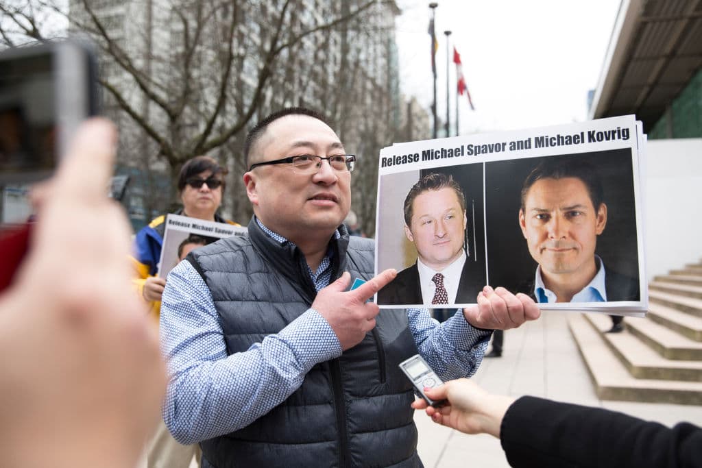 Louis Huang, de Vancouver Freedom and Democracy for China, sostiene fotos de los canadienses Michael Spavor y Michael Kovrig, detenidos por China, frente a la Corte Suprema de Columbia Británica, en Vancouver, el 6 de marzo de 2019 (JASON REDMOND/AFP a través de Getty Images)