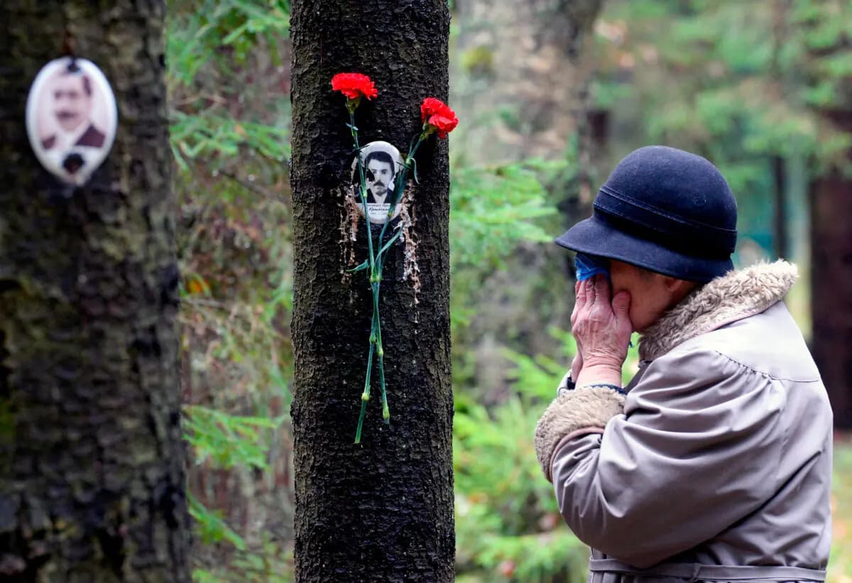 <em>Una mujer reacciona junto al retrato de una víctima de las purgas del dictador soviético Joseph Stalin en el monumento conmemorativo, donde las víctimas fueron enterradas en un bosque a las afueras de San Petersburgo, Rusia, el 30 de octubre de 2017. (Olga Maltseva/AFP vía Getty Images)</em>
