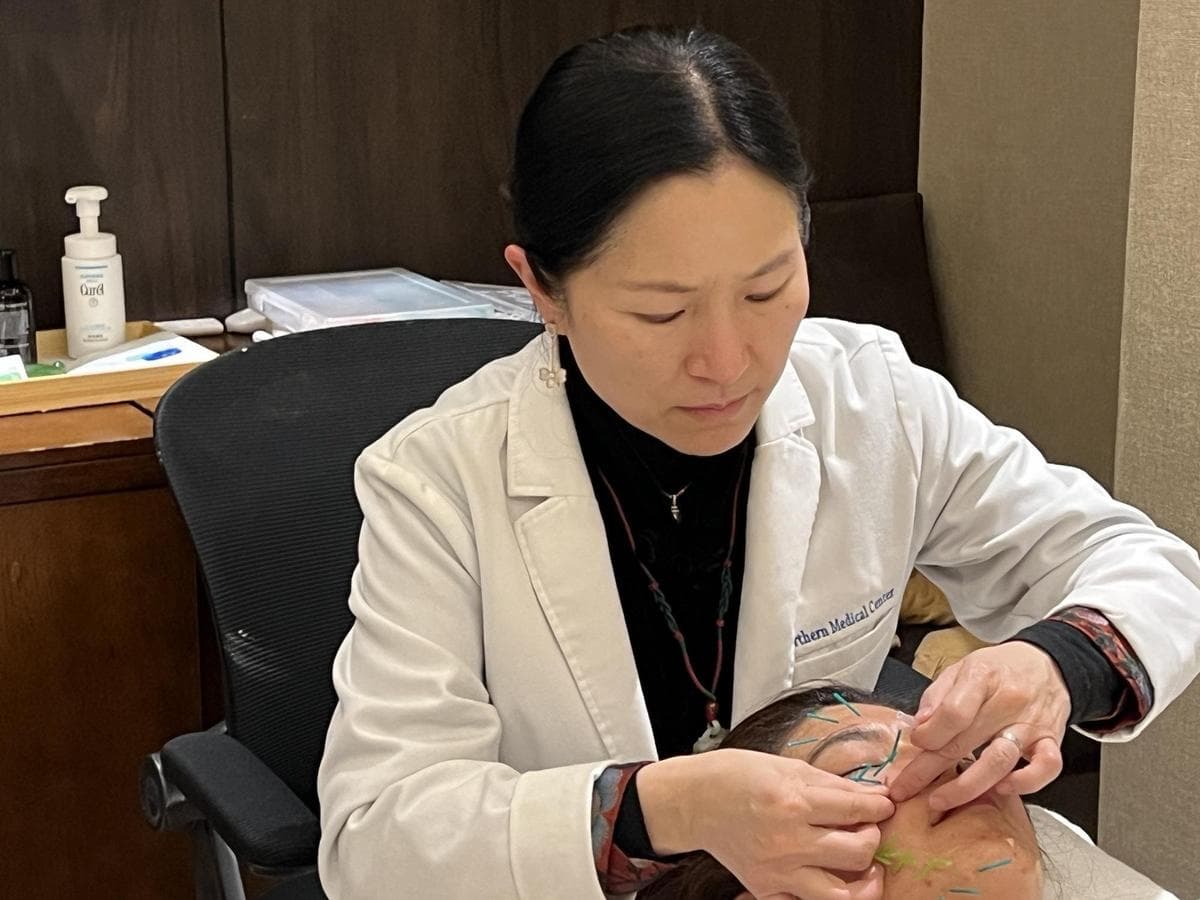 Serene Feng realizando acupuntura facial a una paciente. (Fenni Zhao/The Epoch Times)