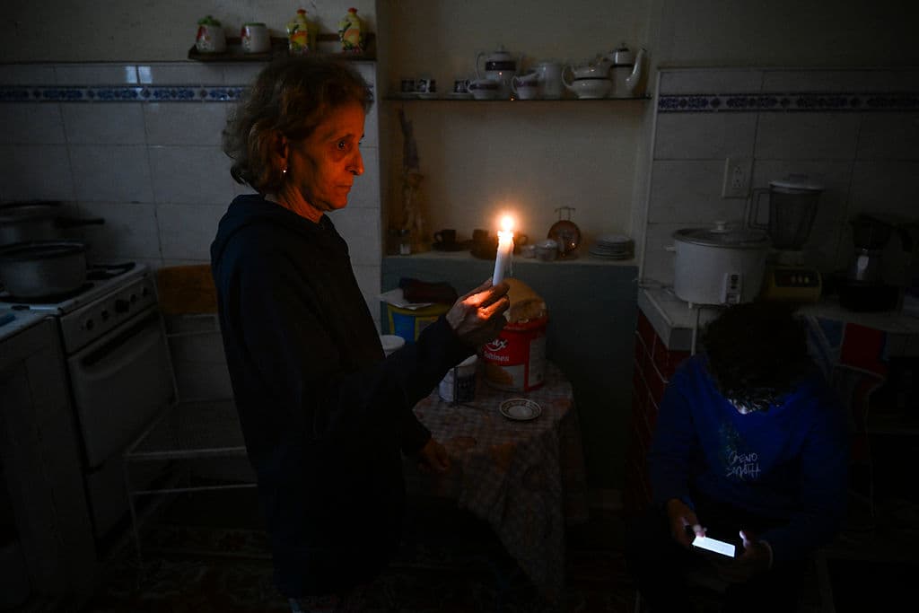 <em>Una mujer sostiene una vela mientras un niño revisa su celular durante un apagón en el barrio de Luyano, La Habana, el 28 de enero de 2026. (Foto de YAMIL LAGE / AFP vía Getty Images)</em>