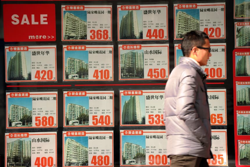 Un hombre caminando frente al escaparate de una agencia inmobiliaria en Shanghái, China, el 4 de diciembre de 2012. (Peter Parks/AFP vía Getty Images).