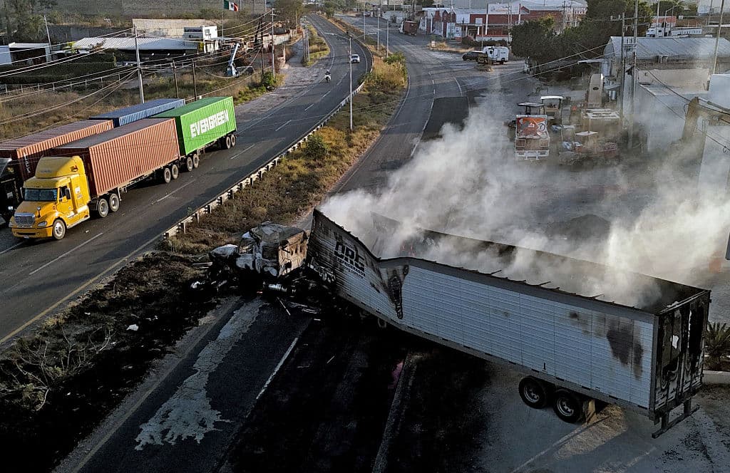 <em>Esta vista aérea muestra un camión quemado, presuntamente incendiado por grupos del crimen organizado en respuesta a una operación para detener a "El Mencho", en una autopista cerca de Acatlán de Juárez, estado de Jalisco, México, el 22 de febrero de 2026. (Ulises Ruiz/AFP vía Getty Images)</em>