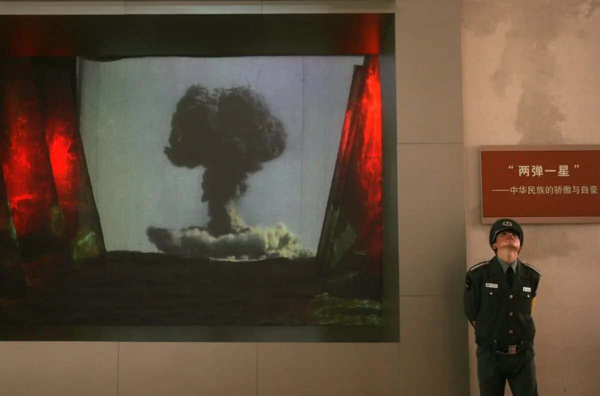 <em>Un guardia de seguridad se encuentra junto a una pantalla que muestra un video sobre la investigación de bombas atómicas y de hidrógeno de China durante una exposición sobre el rejuvenecimiento del régimen chino en el Museo Militar de la Revolución Popular China en Beijing el 17 de octubre de 2007. (China Photos/Getty Images)</em>