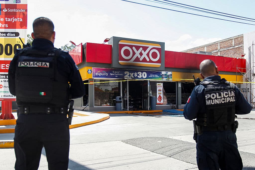 Agentes de la policía estatal mexicana montar guardia una tienda de conveniencia Oxxo que fue presuntamente incendiada por miembros del crimen organizado durante enfrentamientos con las fuerzas gubernamentales en San Francisco del Rincón, estado de Guanajuato, México, el 22 de febrero de 2026. (Mario ARMAS / AFP a través de Getty Images)