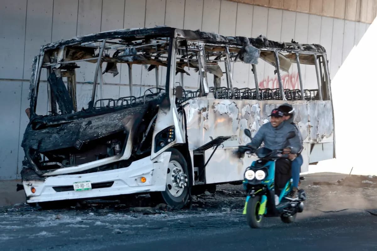 Una motocicleta pasa junto a un autobús quemado que se utilizó para bloquear una avenida en Tonalá, Jalisco, México, el 23 de febrero de 2026. (Ulises Ruiz/AFP a través de Getty Images)