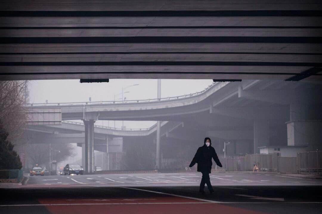 Una mujer china lleva una mascarilla protectora mientras cruza un cruce casi vacío en Beijing, China, el 13 de febrero de 2020. (Kevin Frayer/Getty Images).