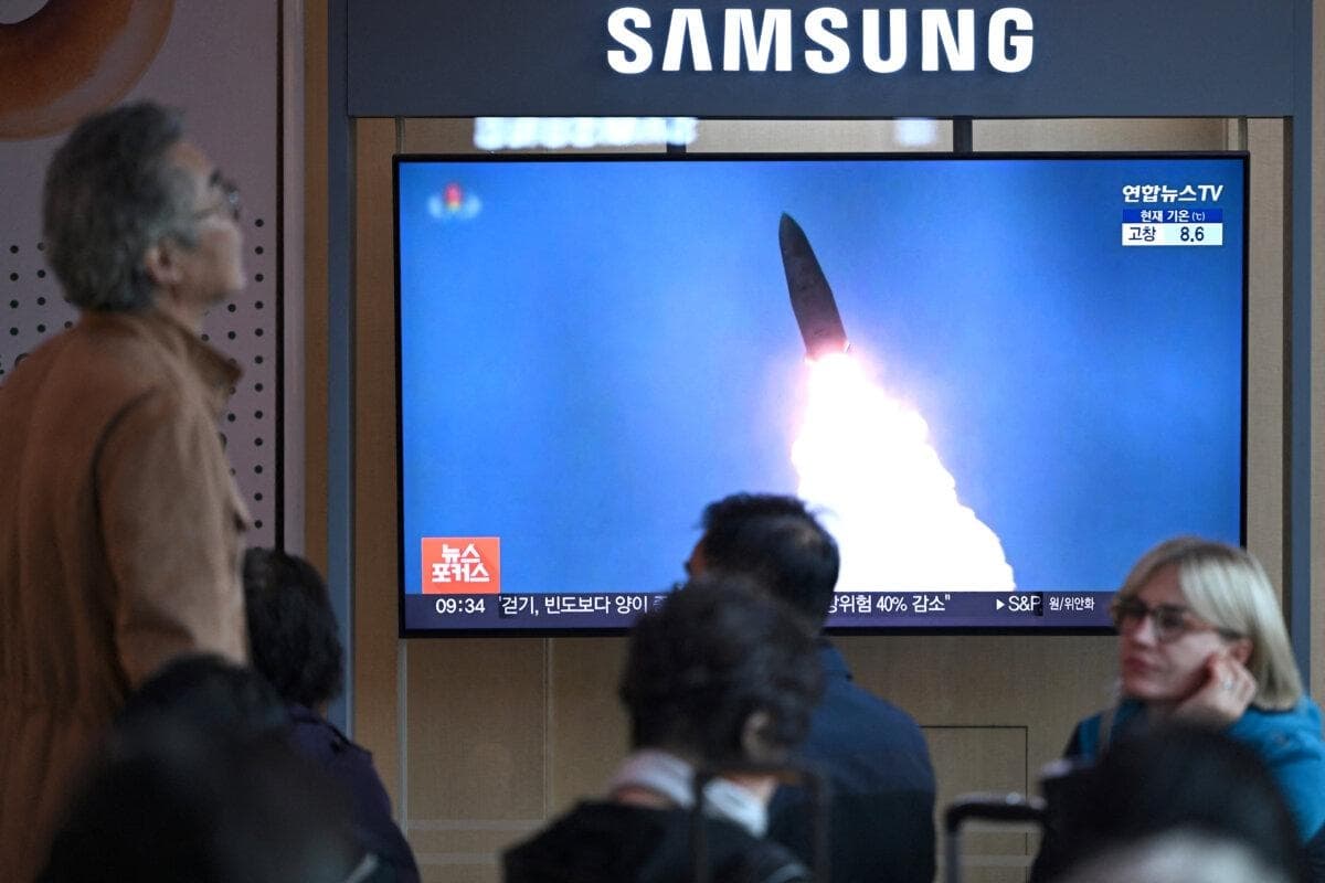 Personas sentadas frente a una pantalla de televisión que muestra un noticiario con imágenes de archivo de una prueba de misiles norcoreana, en una estación de tren de Seúl, Corea del Sur, el 22 de octubre de 2025. (Jung Yeon-je/AFP)
