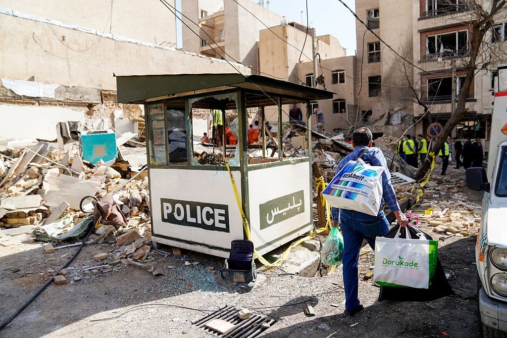 Esta imagen de la agencia de noticias iraní ISNA, muestra a un hombre iraní con bolsas mientras camina entre los escombros de un edificio destruido tras un ataque con misiles en un barrio de la capital iraní, Teherán, el 28 de febrero de 2026, en ataques contra Irán. La Media Luna Roja Iraní informó la noche del 28 de febrero que al menos 201 personas murieron y 747 resultaron heridas en los ataques. (Foto de AMIR KHOLOUSI / ISNA / AFP vía Getty Images)