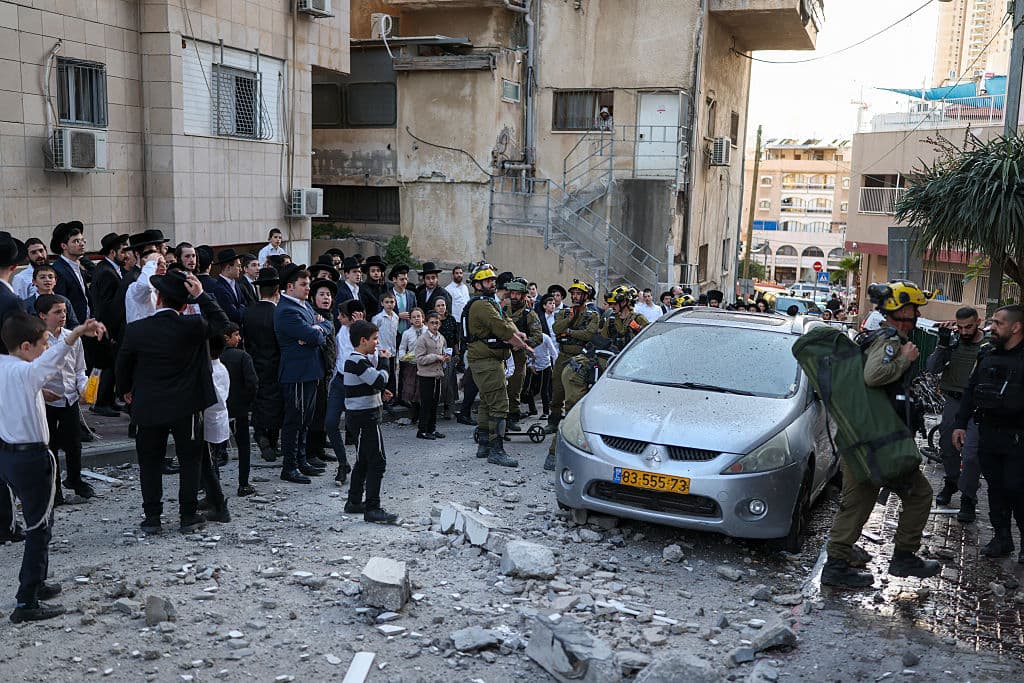 <em>Los equipos de emergencia israelíes llegan al lugar donde cayeron restos de un cohete interceptado en un barrio a las afueras de Tel Aviv el 28 de febrero de 2026. Estados Unidos e Israel lanzaron ataques contra Irán el 28 de febrero. La emisora ​​pública israelí informó que el líder supremo iraní había sido el objetivo, mientras que la república islámica respondió con descargas de misiles contra los países del Golfo e Israel. (Foto de Ilia YEFIMOVICH / AFP vía Getty Images)</em>