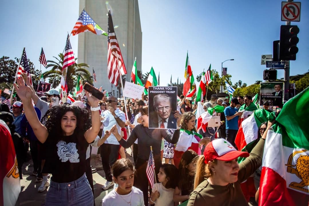 Una mujer sostiene un retrato del presidente de Estados Unidos, Donald Trump, en el que se lee "gracias", mientras la gente ondea banderas estadounidenses e iraníes anteriores a la Revolución Islámica de 1979 y miembros de la comunidad iraní celebran frente al Edificio Federal en el barrio de West LA de Los Ángeles, el 28 de febrero de 2026. (Apu Gomes/AFP vía Getty Images)