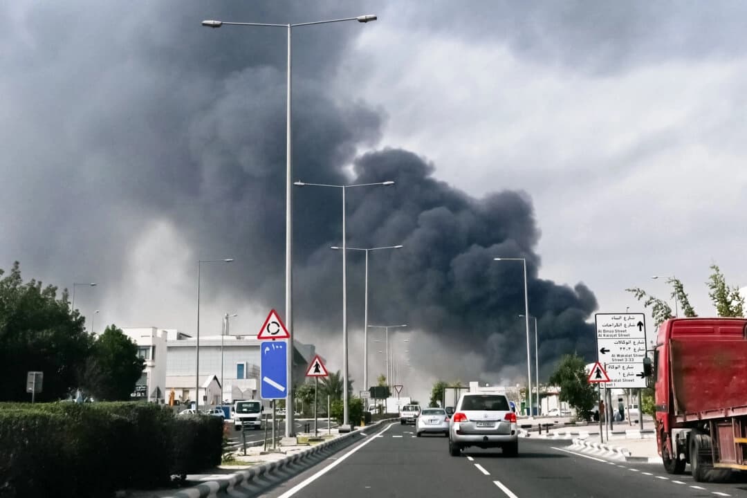 Automovilistas pasan junto a una columna de humo que se eleva desde un supuesto ataque iraní en el distrito industrial de Doha, Qatar, el 1 de marzo de 2026.   (Mahmud HAMS / AFP vía Getty Images)

