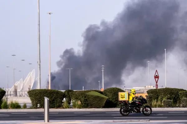 Un ciclista de reparto de comida cerca de una columna de humo que se eleva desde el puerto de Zayed tras un supuesto ataque iraní en Abu Dabi, Emiratos Árabes Unidos, el 1 de marzo de 2026. (Ryan Lim / AFP vía Getty Images)
