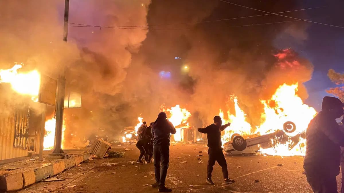 Manifestantes iraníes se reúnen alrededor de autos en llamas mientras bloquean una calle durante una protesta en Teherán, Irán, el 8 de enero de 2026. (Aghasht/Middle East Images/AFP vía Getty Images)