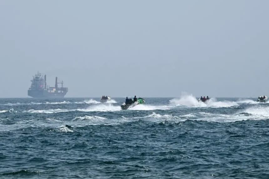 Pequeñas embarcaciones cargadas de mercancías navegan junto al buque portacontenedores Marsa Victory, con bandera de San Cristóbal y Nieves, en las aguas del estrecho de Ormuz, frente a la costa de Khasab, en la península de Musandam, al norte de Omán, el 25 de junio de 2025. (GIUSEPPE CACACE/AFP a través de Getty Images).