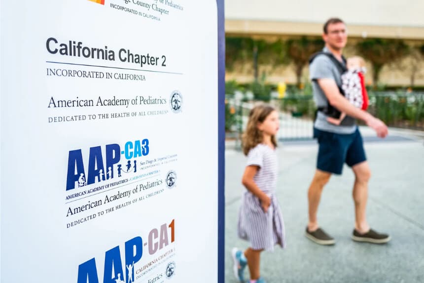 La gente pasa junto a un cartel de una conferencia de la Academia Estadounidense de Pediatría (AAP) en Anaheim, California, el 8 de octubre de 2022. ( John Fredricks/The Epoch Times)