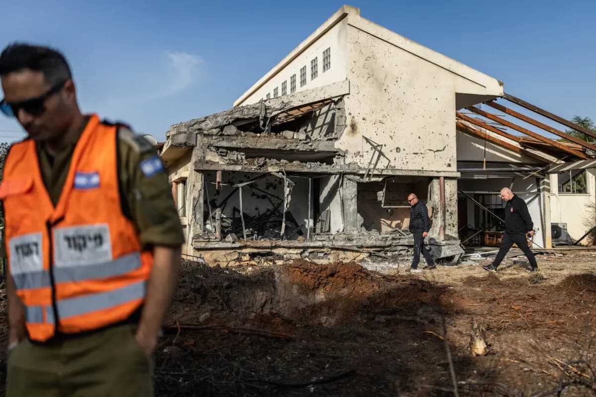 Un miembro del Comando del Frente Interno (izquierda) se encuentra junto a una casa dañada que fue alcanzada por un cohete supuestamente disparado por el grupo militante Hezbolá, respaldado por Teherán, en Haniel, Israel, el 12 de marzo de 2026. (Ilia YEFIMOVICH / AFP vía Getty Images)