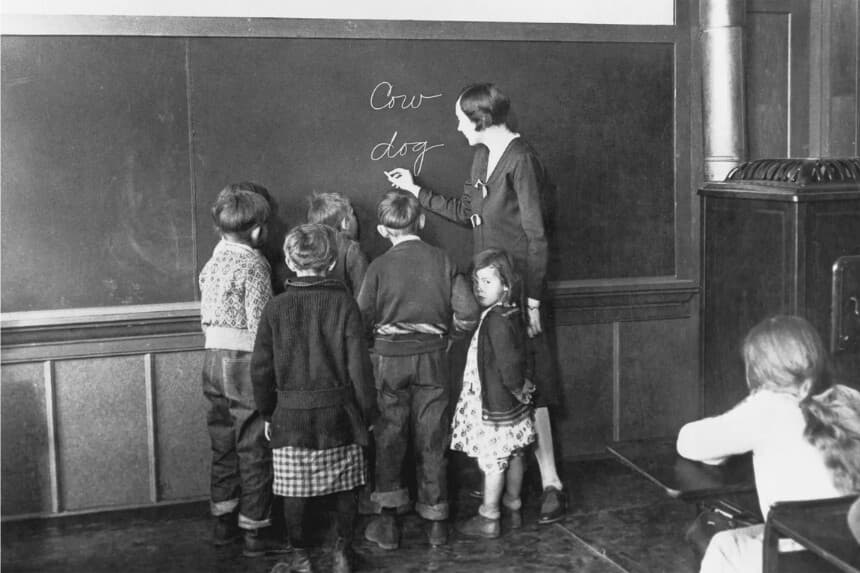 Una profesora escribe nombres de animales en la pizarra para enseñar a sus jóvenes alumnos a deletrear, 1930. (PFPG/Archivo Hulton/Getty Images)