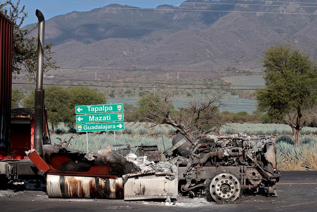<em>Un camión incendiado, utilizado para bloquear carreteras mientras el narcotraficante mexicano "El Mencho" intentaba huir, se ve cerca del "Tapalpa Country Club", donde se escondía al momento de la operación en la que fue abatido, en Tapalpa, estado de Jalisco, México, el 24 de febrero de 2026. Los residentes de Jalisco asomaron la cabeza con cautela el 23 de febrero de 2026 después de que una ola de violencia de represalia por parte de los cárteles sacudiera el estado mexicano durante el fin de semana tras la muerte de un importante capo de la droga. (Foto de Ulises Ruiz / AFP vía Getty Images)</em>