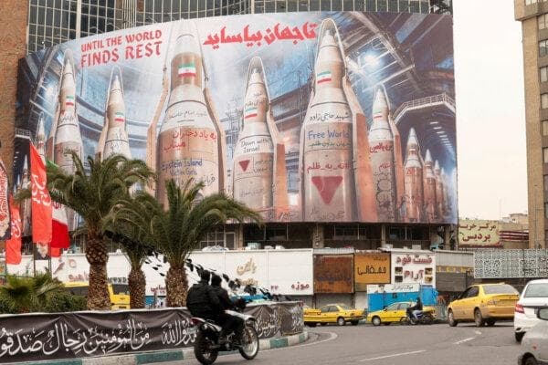 Personas en motocicletas pasan junto a una gran valla publicitaria con imágenes de misiles iraníes en medio del conflicto entre Estados Unidos e Israel con Irán, en Teherán, Irán, el 15 de marzo de 2026. (Alaa Al-Marjani/Reuters)