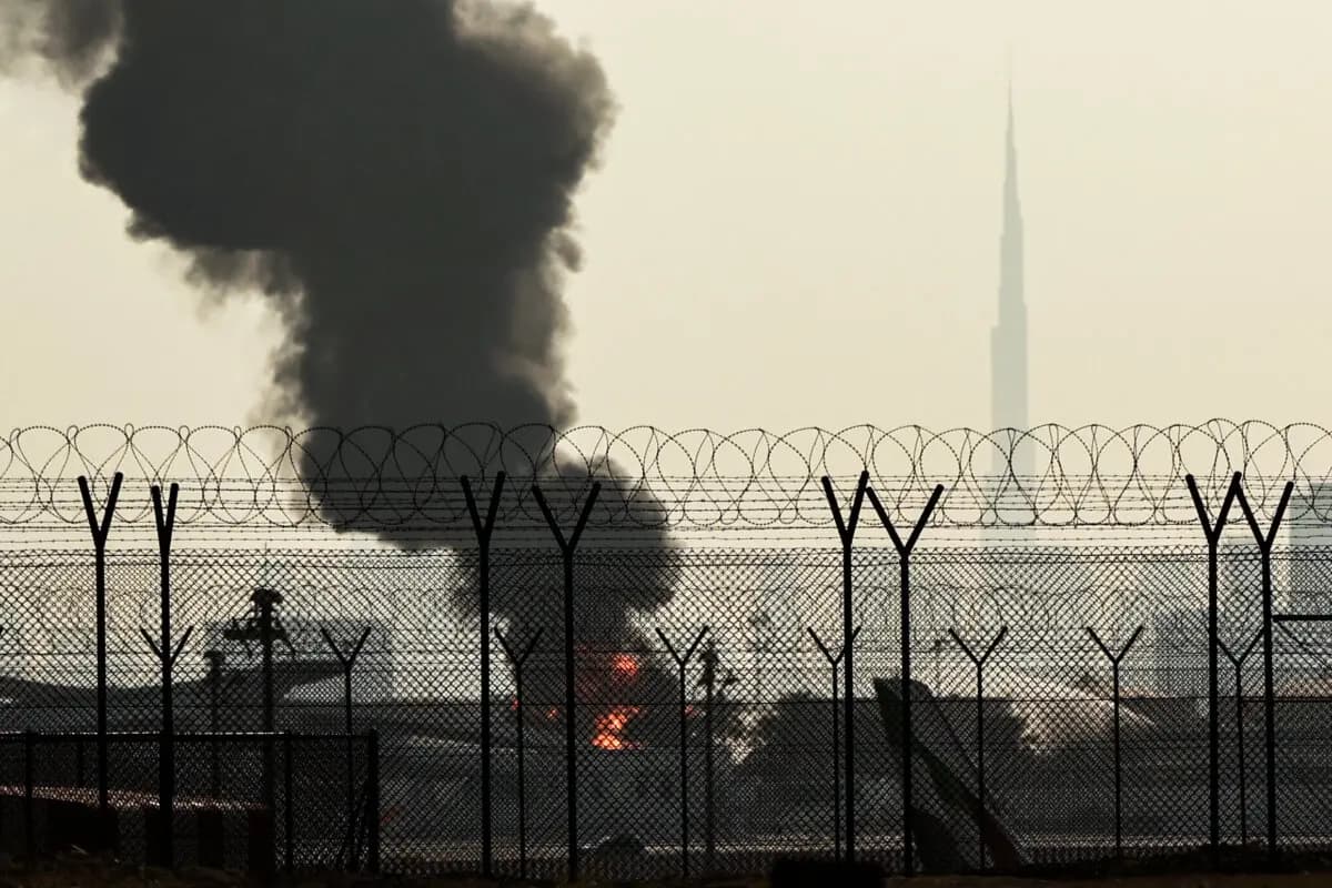 En la imagen se aprecia el perfil urbano de Dubái, con el emblemático rascacielos Burj Khalifa (a la derecha), mientras una columna de humo se eleva desde un incendio que se está produciendo cerca del Aeropuerto Internacional de Dubái el 16 de marzo de 2026. (AFP vía Getty Images).