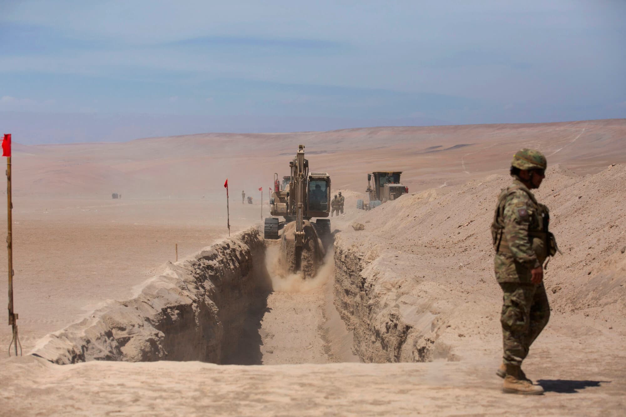 <em>Un soldado monta guardia mientras la maquinaria pesada trabaja cerca del puesto fronterizo de Chacalluta, en la frontera entre Chile y Perú, el 16 de marzo de 2026. (Patricio BANDA / AFP vía Getty Images)</em>
