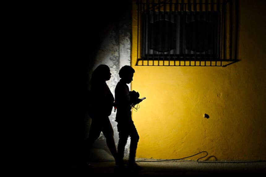 Una mujer sostiene una linterna mientras camina junto a un hombre por una calle durante un apagón en La Habana el 16 de marzo de 2026. Cuba sufrió un apagón generalizado el 16 de marzo de 2026, según la empresa nacional de electricidad, en un contexto de grave crisis en la isla provocada por el bloqueo energético de Estados Unidos. (Yamil LAGE / AFP vía Getty Images).