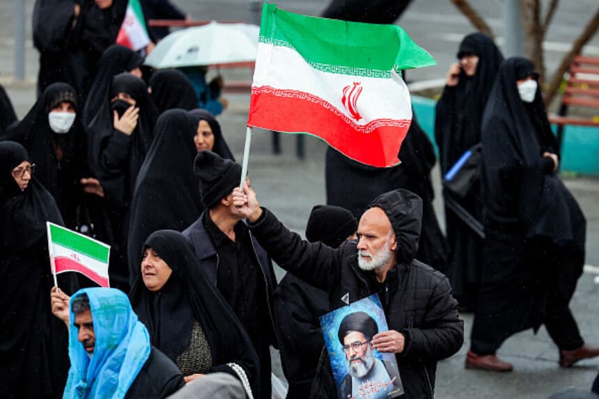 Un doliente sostiene una bandera iraní y una fotografía del líder iraní asesinado, el ayatolá Alí Jamenei, mientras marcha junto a otras personas durante la ceremonia fúnebre del ministro de Inteligencia iraní asesinado, Esmail Khatib, y su familia, tras la oración musulmana semanal del viernes al mediodía en Teherán, el 20 de marzo de 2026. El ejército israelí declaró el 18 de marzo que no detendría su "serie de eliminaciones" de altos cargos iraníes, tras anunciar que había matado a Khatib. (AFP vía Getty Images).