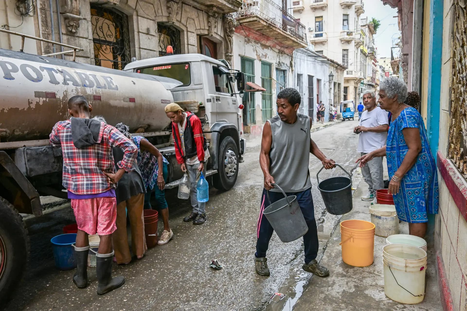 Varias personas esperan para llenar sus bidones y cubos desde un camión cisterna en La Habana, el 20 de marzo de 2026. (Yamil Lage/AFP vía Getty Images)