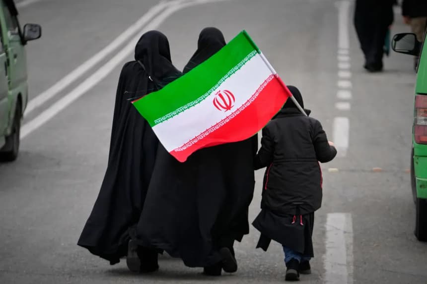 Dos mujeres y un niño con una bandera iraní caminan hacia la Gran Mezquita del Imán Jomeini para asistir a la oración del viernes en Teherán, Irán, el 20 de marzo de 2026. (Vahid Salemi/AP Photo)