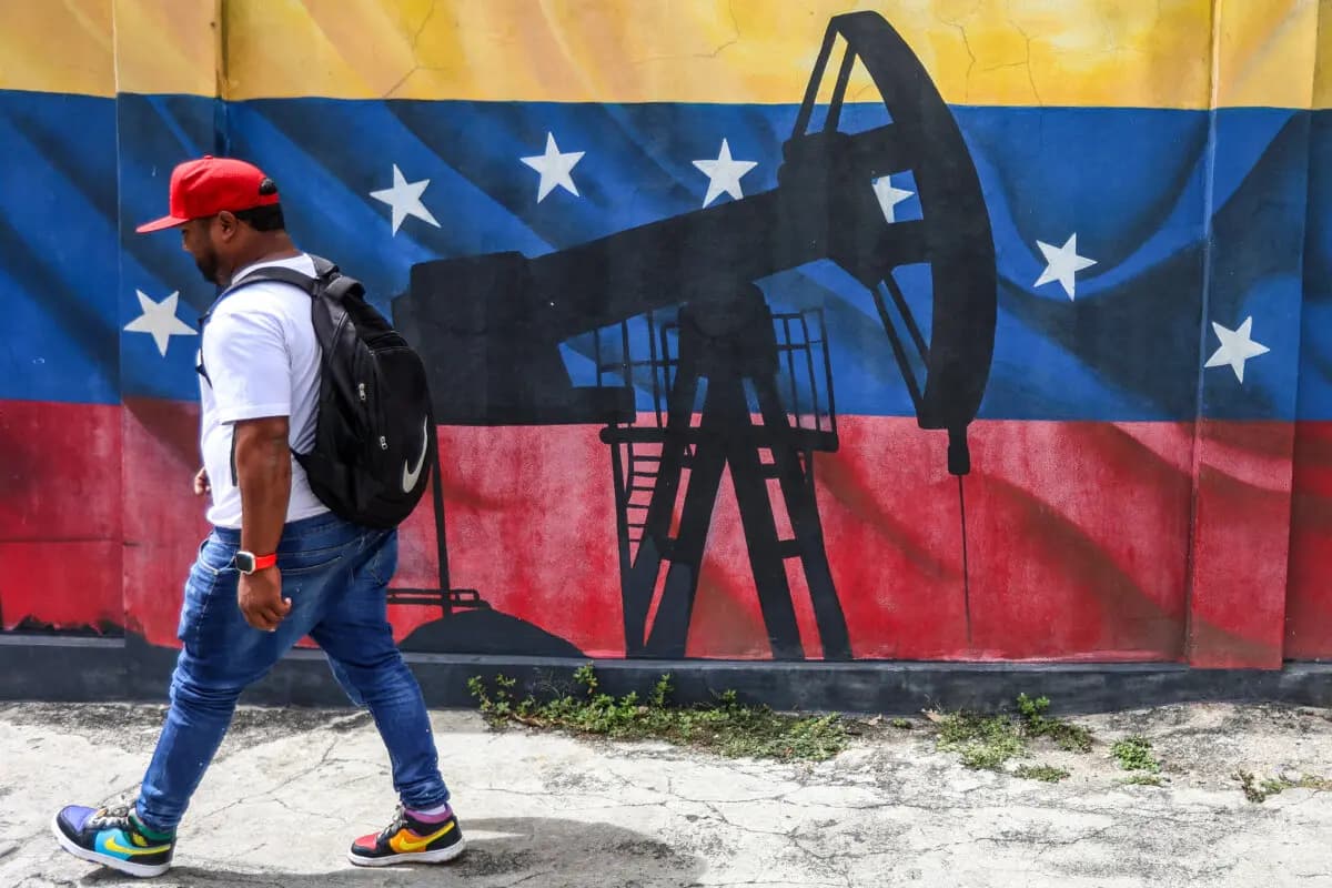 Un hombre pasa junto a un mural que representa una bomba de extracción de petróleo sobre una bandera venezolana en Caracas, el 15 de enero de 2026. (Pedro Mattey/AFP vía Getty Images).