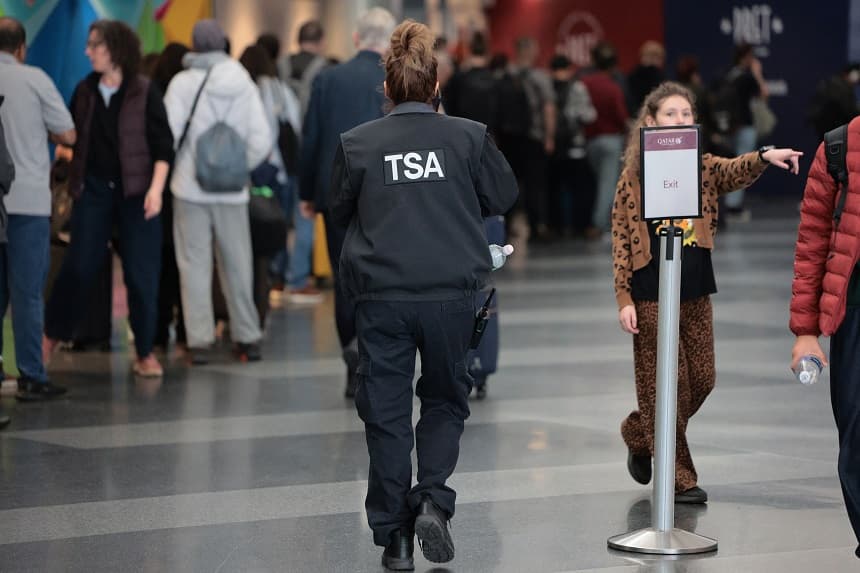 Un agente de la TSA pasa junto a los viajeros que esperan en fila para pasar el control de seguridad en la Terminal 8 del Aeropuerto Internacional John F. Kennedy, el 27 de marzo de 2026 en Nueva York. (Michael M. Santiago/Getty Images)