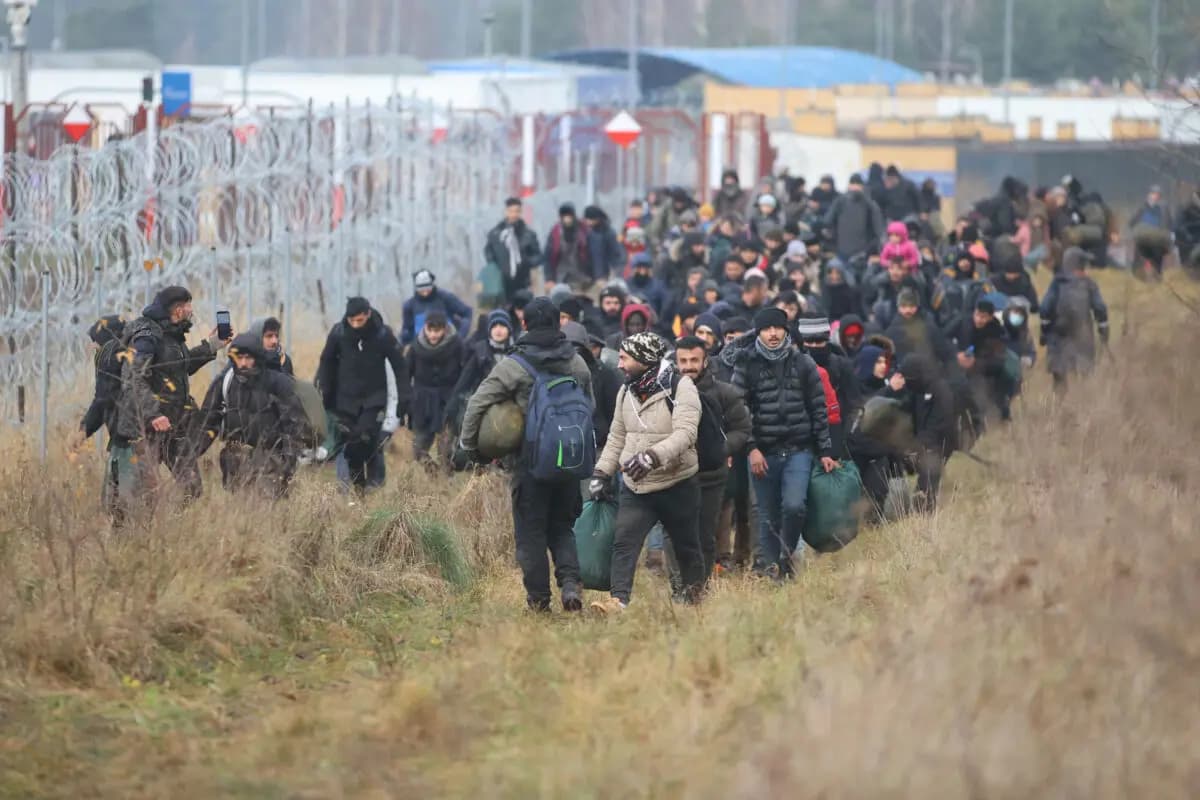 Un grupo de migrantes se desplaza a lo largo de la frontera entre Bielorrusia y Polonia hacia un campamento para unirse a los que se han reunido en el lugar con el objetivo de entrar en Polonia, miembro de la Unión Europea, en la región de Grodno, en Bielorrusia, el 12 de noviembre de 2021. (Leonid Shcheglov/Belta/AFP vía Getty Images)