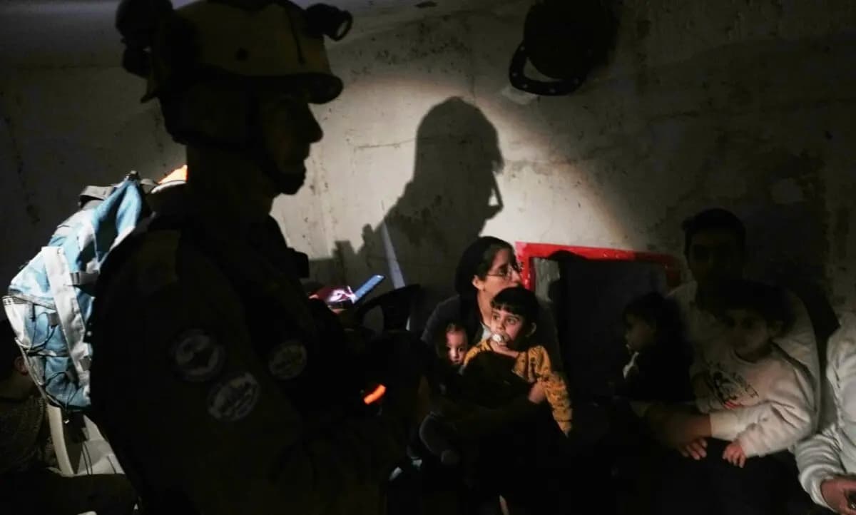 Los equipos de rescate y los residentes se refugian al sonar las sirenas junto a un lugar alcanzado por un misil iraní en Bnei Brak, Israel, el 1 de abril de 2026. (Oded Balilty/AP).