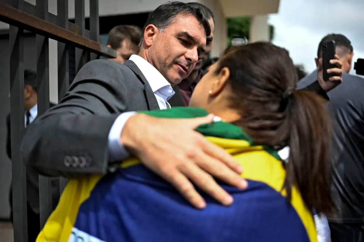 <em>El senador Flavio Bolsonaro, hijo del expresidente brasileño Jair Bolsonaro, saluda a un simpatizante al salir de la sede de la Policía Federal, donde su padre se encuentra detenido, en Brasilia, el 9 de diciembre de 2025. (Ton MOLINA/AFP).</em>