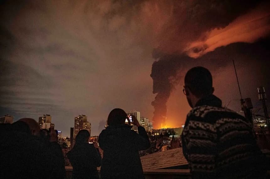 Los residentes observan y toman fotografías mientras las llamas y el humo se elevan desde una instalación de almacenamiento de petróleo alcanzada por los ataques que golpearon la ciudad durante la campaña militar estadounidense-israelí en Teherán, Irán, el 7 de marzo de 2026. (Alireza Sotakbar/ISNA vía AP)