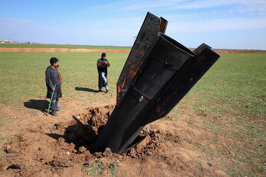 <em>Personas frente a un misil iraní que cayó cerca del Aeropuerto Internacional de Qamishli, cerca de la frontera turca en el distrito de Qamishli en Hasakah, Siria, el 4 de marzo de 2026, en medio del conflicto de EE. UU-Isarel con Irán. (Amjad Kurdo / Middle East Images / AFP via Getty Images)</em>