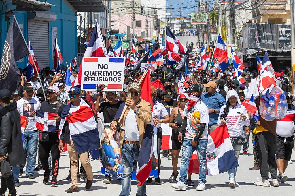 <em>Simpatizantes del grupo nacionalista "Antigua Orden Dominicana" ondean banderas de la República Dominicana durante una marcha contra la inmigración haitiana en Bávaro, provincia de La Altagracia, República Dominicana, el 30 de marzo de 2025. La protesta contra la migración ilegal, convocada con motivo del 181 aniversario de la batalla contra la invasión haitiana, terminó con gases lacrimógenos lanzados por la policía. (Foto de ERICKSON POLANCO/AFP vía Getty Images)</em>