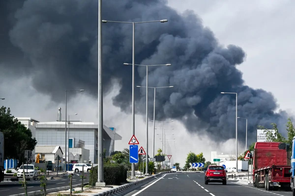 Los automovilistas pasan junto a una columna de humo que se eleva tras un supuesto ataque iraní en el distrito industrial de Doha, Catar, el 1 de marzo de 2026. (Mahmud Hams/AFP vía Getty Images)