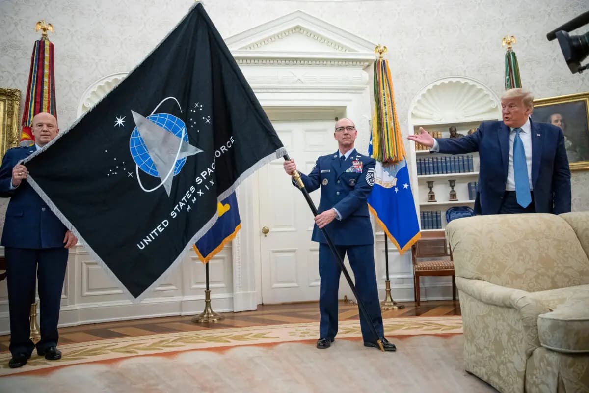 El general John «Jay» Raymond (izquierda), comandante del Mando Espacial de EE. UU., y el sargento mayor Roger Towberman (centro) sostienen la bandera de la Fuerza Espacial mientras el presidente Donald Trump la señala con un gesto durante la presentación en el Despacho Oval de la Casa Blanca en Washington el 15 de mayo de 2020. (Foto AP/Alex Brandon, archivo)