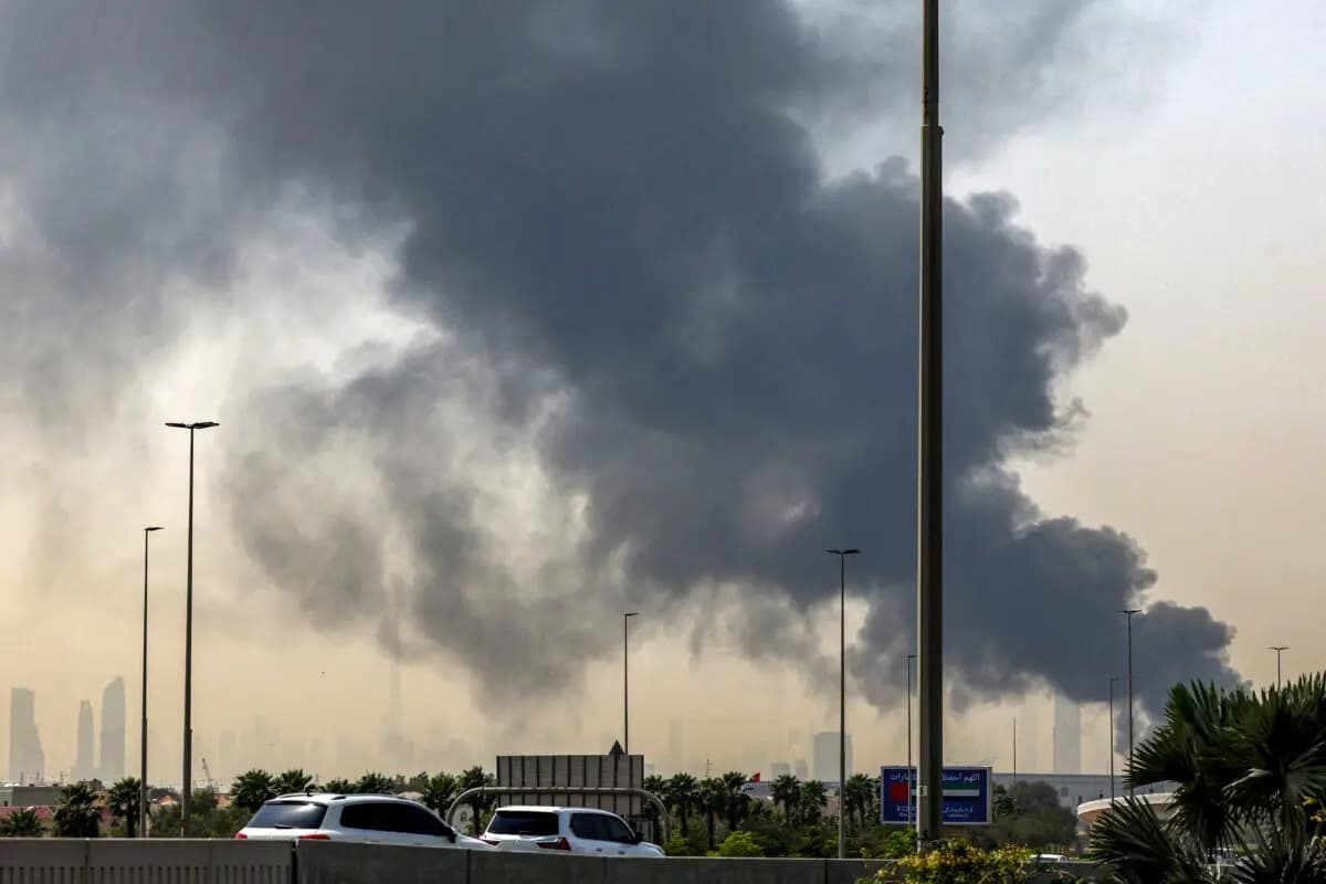 Se muestra el horizonte de Dubái con el emblemático rascacielos Burj Khalifa mientras una columna de humo se eleva desde un incendio en curso cerca del Aeropuerto Internacional de Dubái, en los Emiratos Árabes Unidos, el 16 de marzo de 2026. (Foto de AFP vía Getty Images)