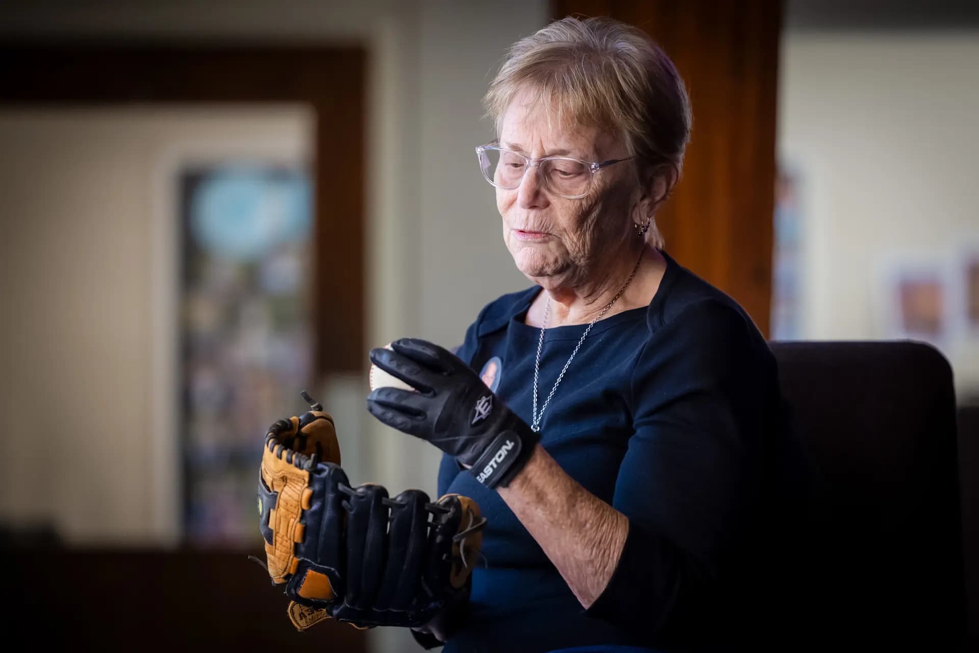 Judy Rogg sostiene una pelota de béisbol y un guante utilizados por su difunto hijo Erik en Los Ángeles el 15 de abril de 2026. (John Fredricks/The Epoch Times)