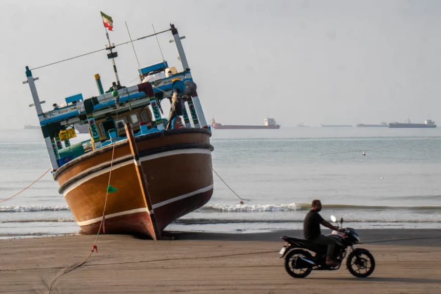 Un hombre iraní pasa en motocicleta junto a un barco en la playa de Suru, en Bandar Abbas, Irán, el 24 de abril de 2026. (Razieh Poudat/ISNA/AFP vía Getty Images)