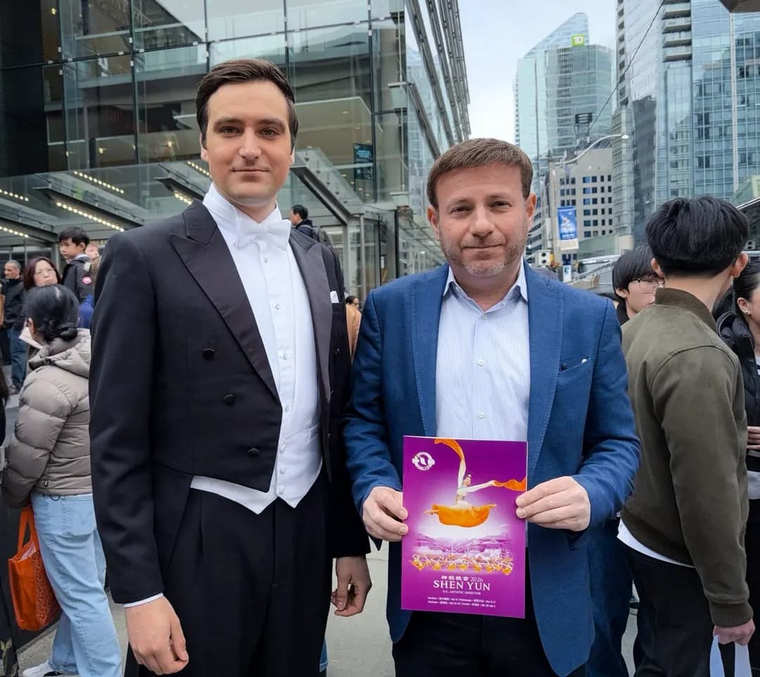 El diputado conservador Roman Baber sostiene un programa de Shen Yun mientras posa junto a un presentador del espectáculo frente al Four Seasons Centre for the Performing Arts de Toronto el 29 de marzo de 2026. (The Epoch Times)