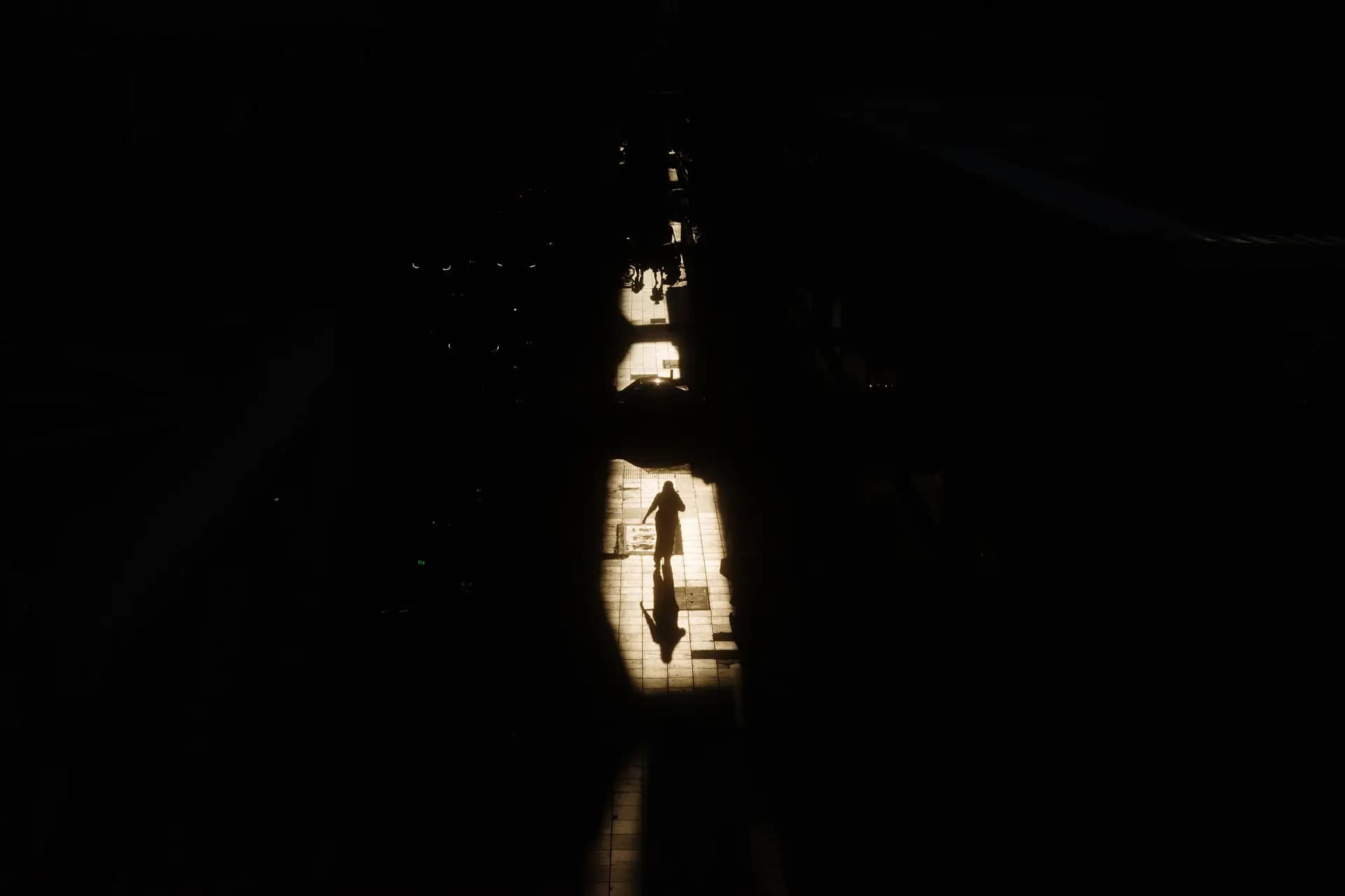 La silueta de un peatón se recorta contra el sol que se filtra a través de las grietas de una acera en Bangkok, el 29 de abril de 2026. (Anthony Wallace/AFP vía Getty Images).