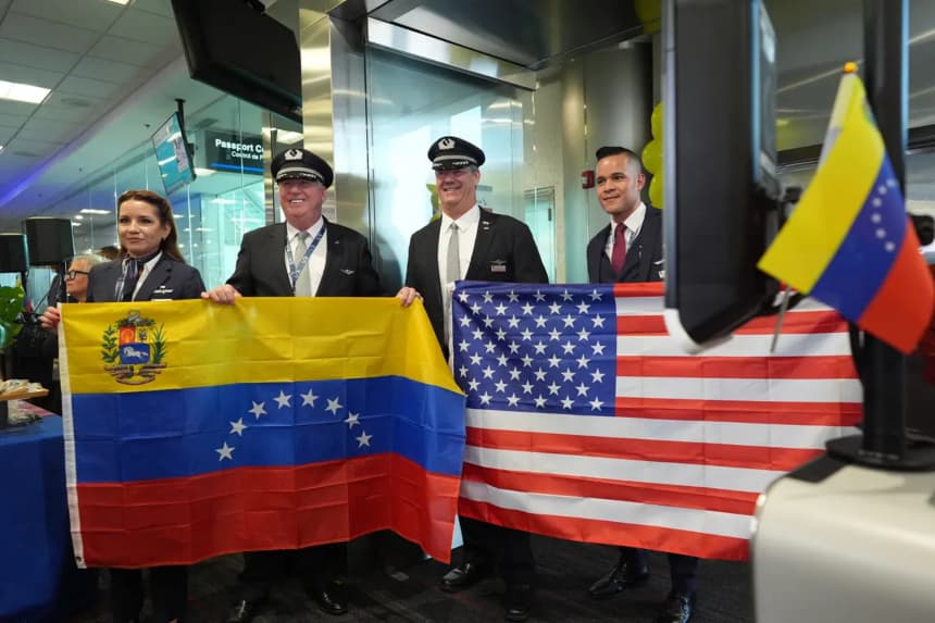 El capitán Ric Wilson (centro izquierda) y el primer oficial Robert Neider (centro derecha) sostienen las banderas de Venezuela y Estados Unidos junto con otros miembros de la tripulación del vuelo AA3599 de American Airlines, mientras se preparan para pilotar el primer vuelo comercial directo entre Estados Unidos y Venezuela en siete años en el Aeropuerto Internacional de Miami, el jueves 30 de abril de 2026. (AP/Rebecca Blackwell)