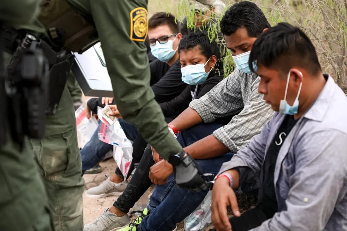 Un agente de la Patrulla Fronteriza revisa a un inmigrante ilegal que lleva dos pulseras que los cárteles mexicanos han estado usando para controlar el tráfico de personas hacia Estados Unidos, cerca de Penitas, Texas, el 15 de marzo de 2021. (Charlotte Cuthbertson/The Epoch Times)
